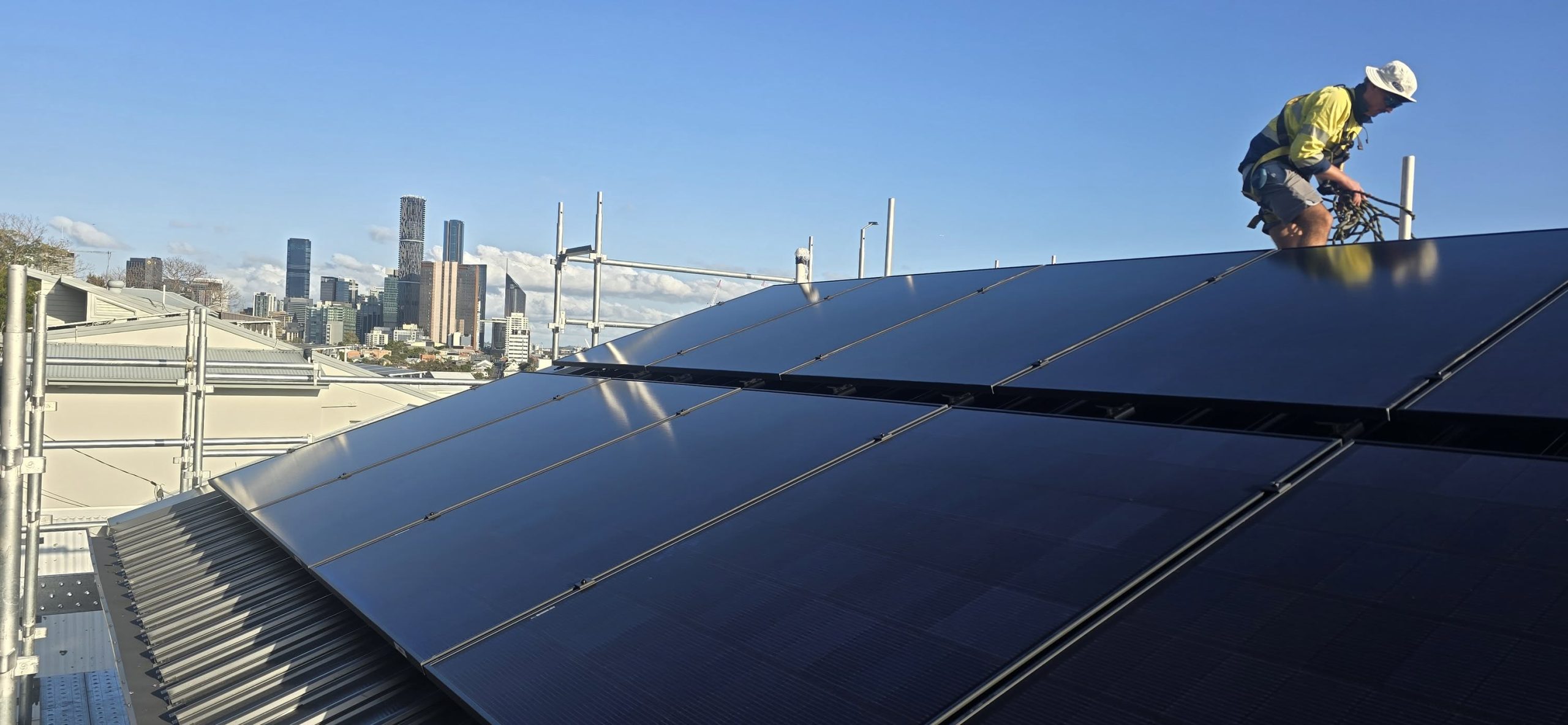 Large-scale commercial solar panel array installation overlooking the Brisbane city skyline by Connect Energy.