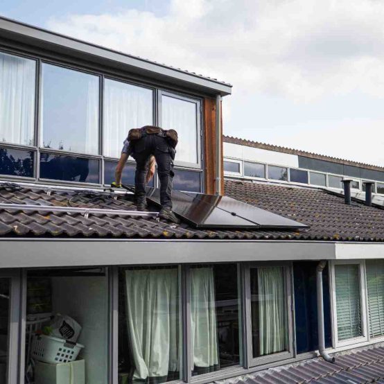 A professional clean-energy technician installing high-efficiency solar panels on the roof of a luxury modern residential property in Bulimba.